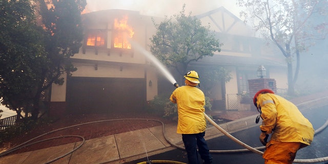 Los Angeles firefighters battle to contain flames on a burning home in the Bel Air district of Los Angeles, Wednesday.