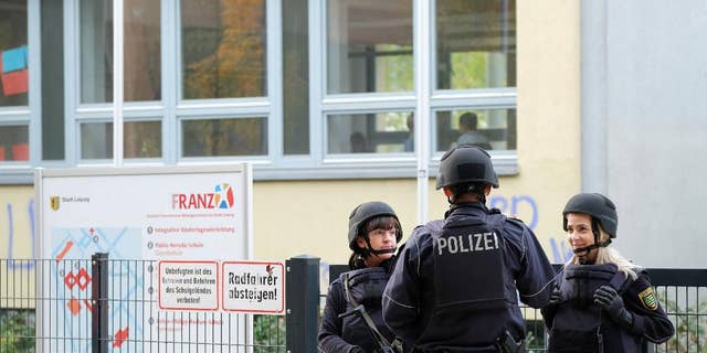 Police stand in front of the Reclam High School in Leipzig, Germany, Monday Oct. 17, 2016.  Police say that schools in at least two German cities have received threats and authorities are working to figure out who and what is behind them. Police in Leipzig said at least seven schools in Leipzig received threats by emails on Monday, though it wasn’t clear exactly what was threatened, news agency dpa reported. Officers were sent to the schools, and students and teachers had to remain in the buildings.  ( Sebastian Willnow/dpa via AP)