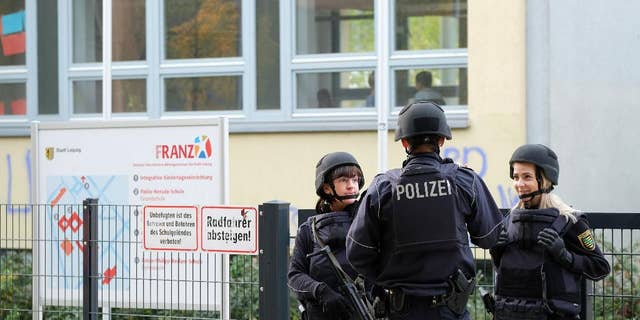 Police stand in front of the Reclam High School in Leipzig, Germany, Monday Oct. 17, 2016. Police say that schools in at least two German cities have received threats and authorities are working to figure out who and what is behind them. Police in Leipzig said at least seven schools in Leipzig received threats by emails on Monday, though it wasn’t clear exactly what was threatened, news agency dpa reported. Officers were sent to the schools, and students and teachers had to remain in the buildings. ( Sebastian Willnow/dpa via AP)