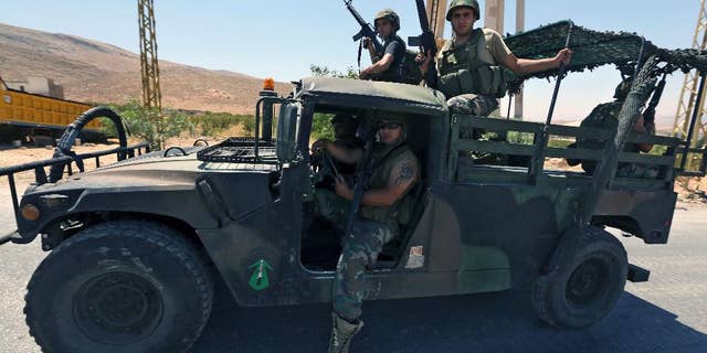 Lebanese army soldiers sit inside a Humvee as reinforcements arrive to the outskirts of Arsal, a predominantly Sunni Muslim town near the Syrian border in eastern Lebanon, Monday, Aug. 4, 2014. Thousands of Lebanese civilians and Syrian refugees packed cars and pickup trucks Monday, fleeing an eastern border town that was overrun by militants from neighboring Syria as Lebanese troops fight to liberate the area. (AP Photo/Bilal Hussein)