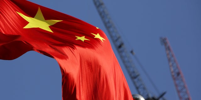 China's national flag is seen in front of cranes on a construction site at a commercial district in Beijing, China, January 26, 2016. REUTERS/Kim Kyung-Hoon - RTX240F5