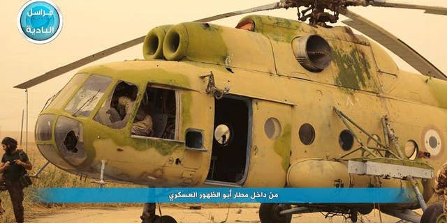 In this image posted on a social media account of Syria's al-Qaida-linked Nusra Front early Thursday Sept. 10, 2015, which is consistent with AP reporting, shows fighters from the group in and around a Syrian government forces helicopter, inside the Abu Zuhour air base, in Idlib province, north Syria. After a two-year siege, al-Qaida's affiliate in Syria and other insurgents on Wednesday captured the one remaining Syrian army air base in Idlib province, a development that activists said effectively expelled the last of President Bashar Assad's military from the northwestern province. The Arabic words read: "from inside Abu Zuhour air base." (Al-Nusra Front social media account via AP)