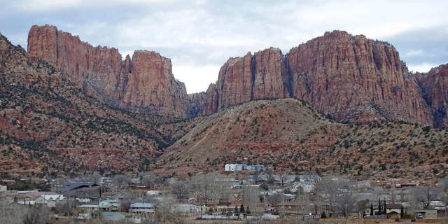 FILE - This Dec. 16, 2014, file photo, shows Hildale, Utah, sitting at the base of Red Rock Cliff mountains, with its sister city, Colorado City, Ariz., in the foreground. The federal government's bid to dismantle the police department in a polygamous community on the Arizona-Utah border has been rejected by a judge as too drastic and expensive. But the towns will still be under court supervision for the next decade as punishment in a religious discrimination case. (AP Photo/Rick Bowmer, File)