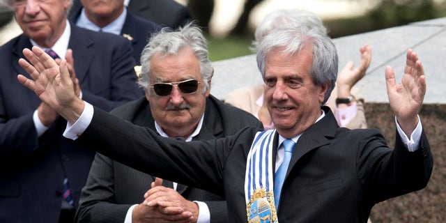 Uruguay's new President Tabare Vazquez waves to the crowd wearing the presidential sash as outgoing President Jose Mujica looks on, behind center, during his inauguration ceremony at Independence Plaza in Montevideo, Uruguay, Sunday, March 1, 2015. (AP Photo/Natacha Pisarenko)