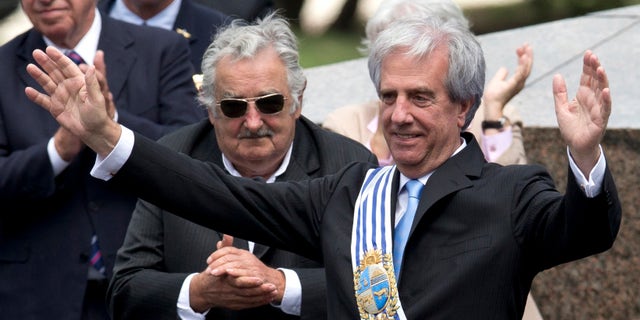Uruguay's new President Tabare Vazquez waves to the crowd wearing the presidential sash as outgoing President Jose Mujica looks on, behind center, during his inauguration ceremony at Independence Plaza in Montevideo, Uruguay, Sunday, March 1, 2015. (AP Photo/Natacha Pisarenko)