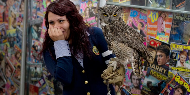 A Harry Potter fan reacts after a live owl bites her, inside an exhibition of the Guinness World Record holding collection of Harry Potter memorabilia, at the Mexican Museum of Antique Toys, in Mexico City, Friday, Feb. 27, 2015. Mexico's fan Menahem Asher Silva Vargas assembled the collection, which contains thousand objects, including figurines, wands, magazines, puzzles, and accessories. (AP Photo/Rebecca Blackwell)