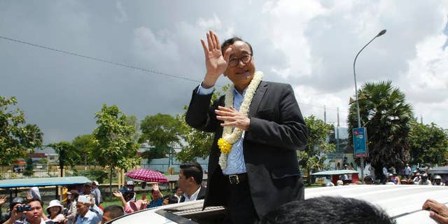 FILE - In this Aug. 16, 2015 file photo, Sam Rainsy, leader of the opposition Cambodia National Rescue Party (CNRP), waves from a car upon his arrival at Phnom Penh International Airport in Phnom Penh, Cambodia as hundreds of cheering supporters greeted him on his return from a trip abroad. The head of Cambodia's opposition party has announced his resignation from the group after the country's long-serving prime minister announced plans for a law that could lead to the party's dissolution. Rainsy announced his resignation Saturday, Feb. 11, 2017 in a letter to his Cambodia National Rescue Party.(AP Photo/Heng Sinith, File)