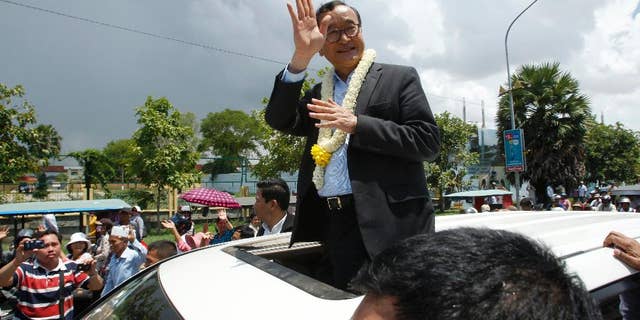 FILE - In this Aug. 16, 2015 file photo, Sam Rainsy, leader of the opposition Cambodia National Rescue Party (CNRP), waves from a car upon his arrival at Phnom Penh International Airport in Phnom Penh, Cambodia as hundreds of cheering supporters greeted him on his return from a trip abroad. The head of Cambodia's opposition party has announced his resignation from the group after the country's long-serving prime minister announced plans for a law that could lead to the party's dissolution. Rainsy announced his resignation Saturday, Feb. 11, 2017 in a letter to his Cambodia National Rescue Party.(AP Photo/Heng Sinith, File)