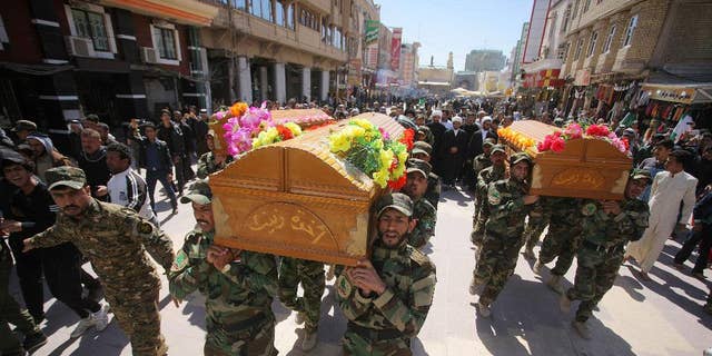 Mourners chant slogans against the Islamic State group during the funeral procession of three members of a Shiite group, Asaib Ahl al-Haq, or League of the Righteous, who were killed in Tikrit while fighting Islamic militants, in Najaf, 100 miles (160 kilometers) south of Baghdad, Iraq, Wednesday, March 11, 2015. Iranian-backed Shiite militias and Sunni tribes have joined Iraq's military in a major operation to retake Tikrit from the Islamic State group.  (AP Photo/Jaber al-Helo)