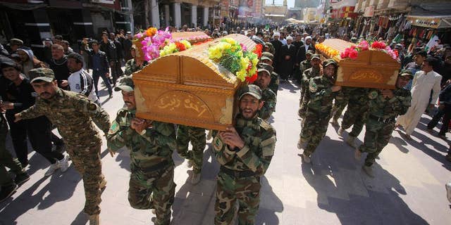 Mourners chant slogans against the Islamic State group during the funeral procession of three members of a Shiite group, Asaib Ahl al-Haq, or League of the Righteous, who were killed in Tikrit while fighting Islamic militants, in Najaf, 100 miles (160 kilometers) south of Baghdad, Iraq, Wednesday, March 11, 2015. Iranian-backed Shiite militias and Sunni tribes have joined Iraq's military in a major operation to retake Tikrit from the Islamic State group. (AP Photo/Jaber al-Helo)