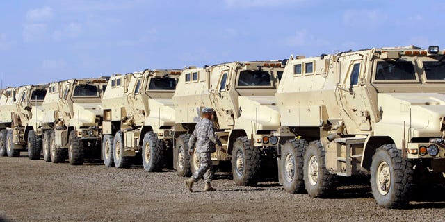 A U.S. soldier walks past armored vehicles that are being readied to ship out of the Camp Victory complex that is set to close in Baghdad, Iraq, on Nov. 7, 2011.