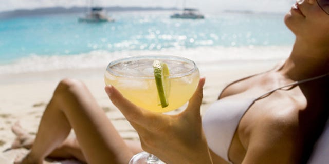 be95f220-woman relaxing at the beach drinking margarita cocktail