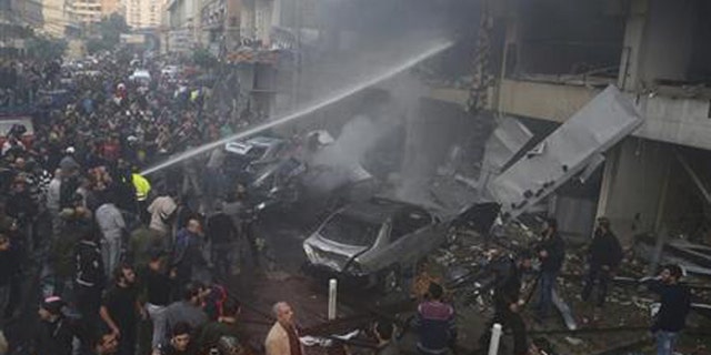 People gather as firefighters attempt to extinguish a fire at the site of an explosion in Beirut's southern suburbs, Jan. 2, 2014. (Reuters)