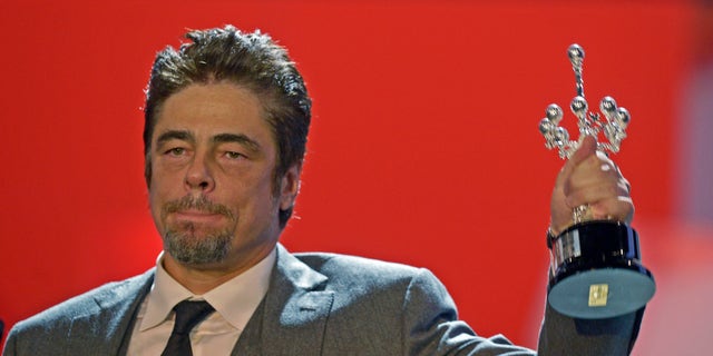 September 26, 2014. Puerto Rican actor Benicio Del Toro holds up his trophy after receiving the Donostia Award for career achievement on the eighth day of the 62nd San Sebastian Film Festival.