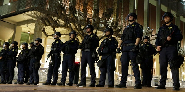 University of California at Berkeley police guard the building where Breitbart News editor Milo Yiannopoulos was to speak Wednesday, Feb. 1, 2017, in Berkeley, Calif. A small group of people with their faces covered broke windows, hurled fireworks at police officers and threw smoke bombs, prompting UC Berkeley officials to cancel Yiannopoulos's talk.