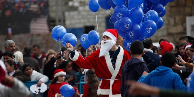 Dec. 24, 2014: A Palestinian dressed as Santa Claus holds balloons at Manger Square, outside the Church of the Nativity, traditionally believed by Christians to be the birthplace of Jesus Christ, in the West Bank city of Bethlehem on Christmas Eve.