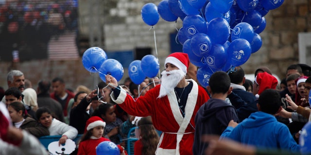 Dec. 24, 2014: A Palestinian dressed as Santa Claus holds balloons at Manger Square, outside the Church of the Nativity, traditionally believed by Christians to be the birthplace of Jesus Christ, in the West Bank city of Bethlehem on Christmas Eve.