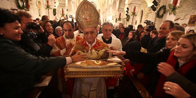 Dec. 25, 2010: Latin Patriarch of Jerusalem Fouad Twal carries the statuette of baby Jesus during the midnight Mass ceremony which marks the beginning of Christmas Day at the Church of the Nativity in the West Bank town of Bethlehem.