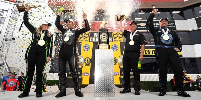 In this photo provided by the NHRA, the four Auto Club NHRA Finals drag races winners from left, Brittany Force, Top Fuel, Eddie Krawiec, Pro Stock Motorcycle, Bo Butner, Pro Stock, and Robert Hight, Funny Car, celebrate on state at Auto Club Raceway, Sunday, Nov. 12, 2017, in Pomona, Calif. (Marc Gewertz/NHRA via AP)