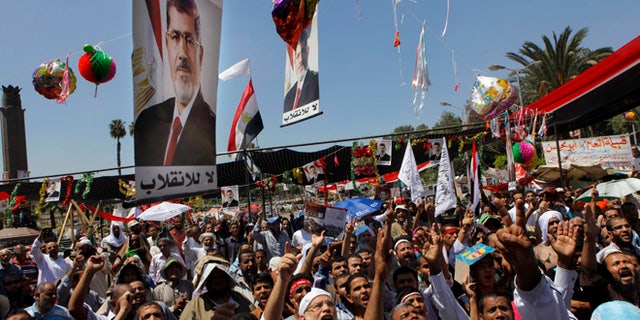 Supporters of Egypt's ousted President Mohammed Morsi shout slogans under his posters following Friday prayers in Nahda square, where protesters installed their camp near Cairo University in Giza, southwest of Cairo, Egypt, Friday, Aug. 9, 2013.