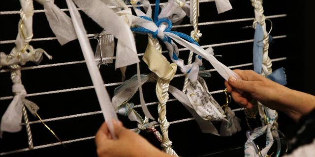 FILE- In this May 22, 2015 file photo, artist Meg Saligman shows knots tied to a mock-up of an art installation at her studio in Philadelphia. The installation is planned to be in the shape of a latticed grotto and will greet Pope Francis and millions of others when they travel to Philadelphia this fall. Visitors will be invited to leave their own problems behind in the form of knots affixed to its walls, or help others by loosening and removing a knot already in place. (AP Photo/Matt Slocum, File)