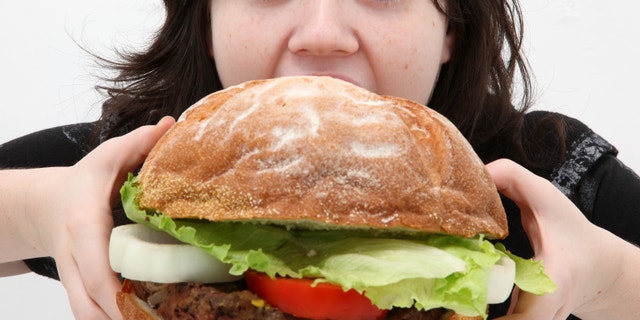 Super huge giant burger and teen girl trying to eat it.