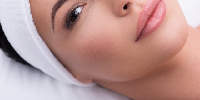 Top view close-up of beautiful woman with lengthened eyelashes. She is lying and looking at camera with confidence