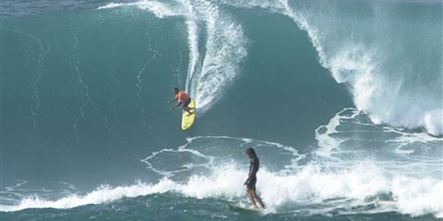 In this Jan. 7, 2002 file photo provided by World Surf League, Clyde Aikau, left, brother of Eddie Aikau, drops into a wave as Tony Ray, of Australia, finishes during the Quiksilver In Memory of Eddie Aikau big wave surf competition at Waimea Bay, Hawaii. (Ronen Zilbermen/World Surf League via AP, File)