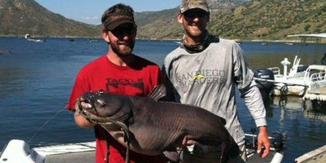 Cameron Smith left, holds his record-breaking blue catfish at El Capitan Reservoir.