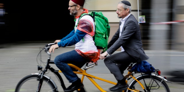 A Muslim and a Jewish man rides a tandem together during a bicycle tandem tour of Jews and Moslems against anti-Semitism and hatred of Muslims in Berlin, Sunday, June 24, 2018. (AP Photo/Markus Schreiber)