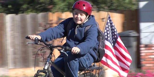 Cody Alicea, 13, rides his bicycle with his American Flag attached.