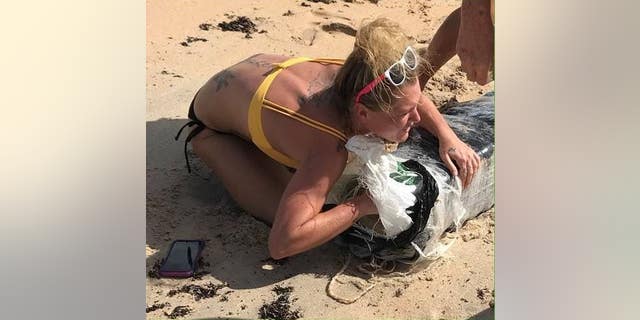 Police are looking to identify a woman who was seen hugging a bundle of marijuana that washed up on a Florida beach.