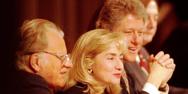 Rev. Billy Graham, left, sits with First Lady Hillary Clinton and President Bill Clinton at the head table during a prayer breakfast.