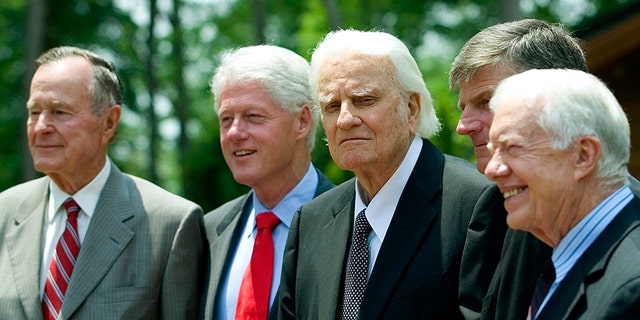 Former U.S. Presidents George H. W. Bush, left, and Bill Clinton, Billy Graham, and former President Jimmy Carter stand together. Graham was a spiritual adviser to each of the men.