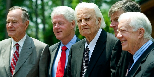 Former U.S. Presidents George H. W. Bush, left, and Bill Clinton, Billy Graham, and former President Jimmy Carter stand together. Graham was a spiritual adviser to each of the men.