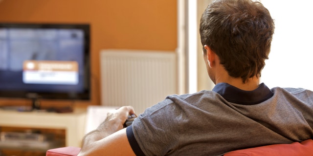 Rear view of young man watching television