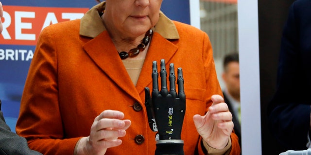 File photo: German Chancellor Angela Merkel looks at a bionic hand during a tour at the CeBIT technology fair in Hanover March 10, 2014. (REUTERS/Fabrizio Bensch)