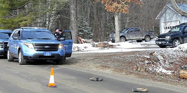 Two Maine State Police troopers consult with each other outside a residence Sunday on Winnecook Road in Burnham while investigating the death of Joyce Wood. A pair of boots lie in the road in foreground.