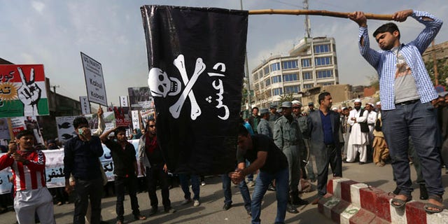 FILE: Oct. 12, 2014: Men prepare to set fire to an Islamic State flag during a protest in Kabul, Afghanistan.