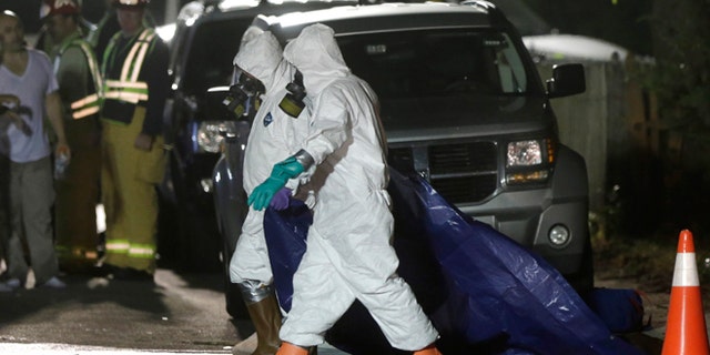 Sept. 11, 2014: Investigators in protective clothing drag a tarp across the street in front of a house where a Massachusetts prosecutor said the bodies of three infants were found in Blackstone, Mass. Worcester County District Attorney Joseph Early Jr. said Thursday authorities don't know when or how the babies died.