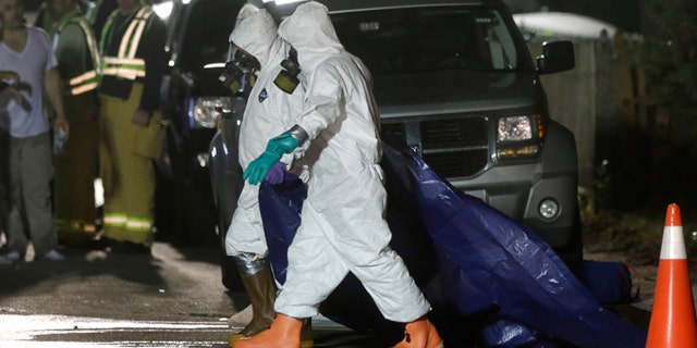 Sept. 11, 2014: Investigators in protective clothing drag a tarp across the street in front of a house where a Massachusetts prosecutor said the bodies of three infants were found in Blackstone, Mass. Worcester County District Attorney Joseph Early Jr. said Thursday authorities don't know when or how the babies died.