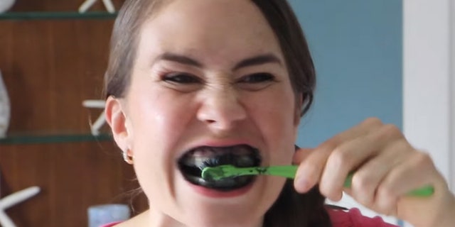 YouTube user "Mama Natural" uses activated charcoal to whiten her teeth.