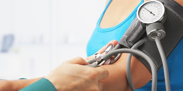 Checking blood pressure of female patient, unrecognizable people