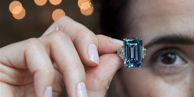 A Christie's employee holds Oppenheimer Blue diamond of 14.62 carats, which is estimated to be sold between 38,000,000 to 45,000,000 US Dollar, during a preview at the auction house Christie's, in Geneva, Switzerland, Thursday, May 12, 2016. The auction will take place on May 18, 2016 in Geneva. (Martial Trezzini/Keystone via AP)
