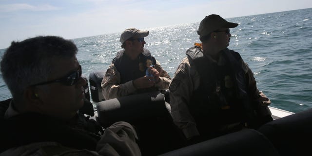 PORT ISABEL, TX - APRIL 12: A boat crew from the U.S. Office of Air and Marine (OAM) looks towards a suspicious boat just across the Mexican border in the Gulf of Mexico on April 12, 2013 near Port Isabel, Texas. The crew patrols coastline waters near the U.S.-Mexico border searching for drug smugglers as well as illegal immigrants, which come across from Mexico near the mouth of the Rio Grande River. The Midnight Express interceptor is a 39 foot 900 horsepower craft capable of chasing smugglers down at 55 knots (63 mph). OAM units also push back illegal fishing boats out of U.S. waters. (Photo by John Moore/Getty Images)