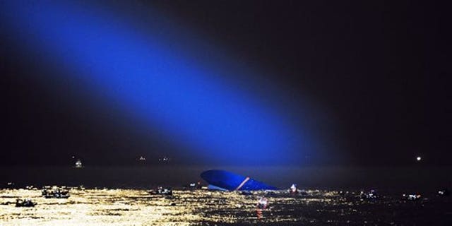 Blue search light cast by South Korean Coast Guard helicopter shows a sunken ferry in the water off the southern coast near Jindo, South Korea, Thursday, April 17, 2014. Fears rose Thursday for the fate of more than 280 passengers still missing more than 24 hours after their ferry flipped onto its side and filled with water off the southern coast of South Korea. (AP Photo/Yonhap) KOREA OUT