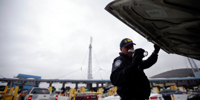 In this Dec. 3, 2014 file photo, a U.S. Customs and Border Protection (CBP) officer checks under the hood of a car as it waits to enter the United States from Tijuana, Mexico through the San Ysidro port of entry in San Diego. Taking a polygraph became a hiring requirement at CBP in 2012 after a huge hiring surge led to more agents getting arrested for misconduct. (AP Photo/Gregory Bull)