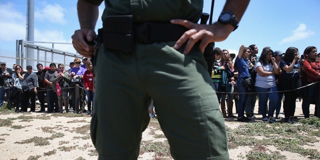SAN DIEGO, CA - APRIL 30: A U.S. Border Patrol agent stands guard as families prepare to meet loved ones at the U.S.-Mexico Border fence during a "Opening the Door of Hope" event on April 30, 2016 in San Diego, California. Five families, with some members living in Mexico and others in the United States, were permitted to meet and embrace for three minutes each at a door in the fence, which the U.S. Border Patrol opened to celebrate Mexican Children's Day. It was only the third time the fence, which separates San Diego from Tijuana, had been opened for families to briefly reunite. The event was planned by the immigrant advocacy group Border Angels. (Photo by John Moore/Getty Images)