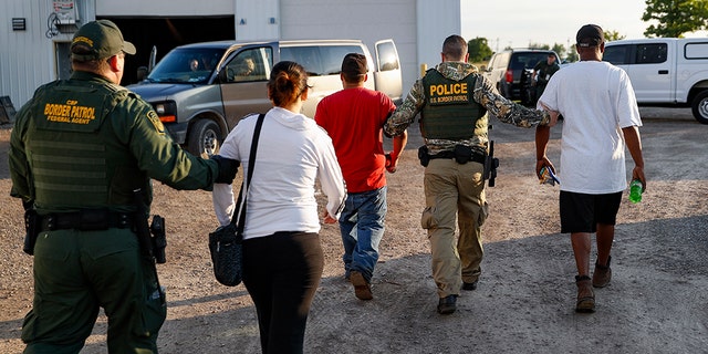 Government agents take suspects into custody during an immigration sting at Corso's Flower and Garden Center in Castalia, Ohio, Tuesday.