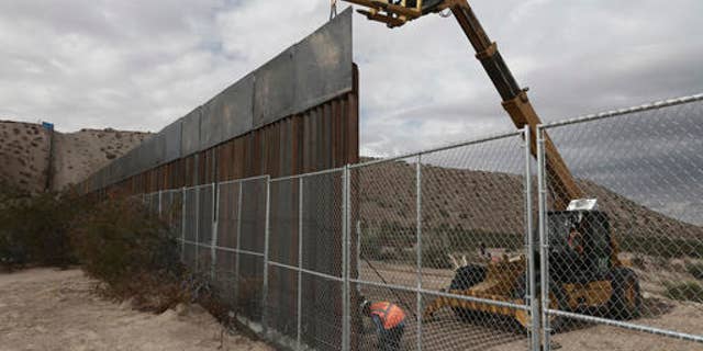 In this Nov. 10, 2016 file photo, workers raise a taller fence along the Mexico-US border between the towns of Anapra, Mexico and Sunland Park, New Mexico